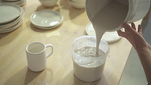 在工作间的碗里陶工倒水漆加工陶土杯