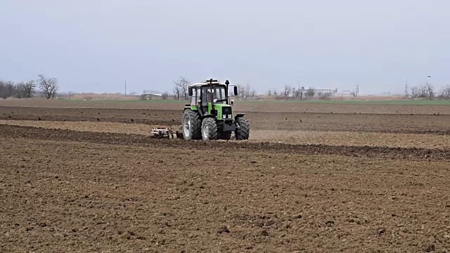 播种前要把地里的土壤弄松。拖拉机用犁犁地