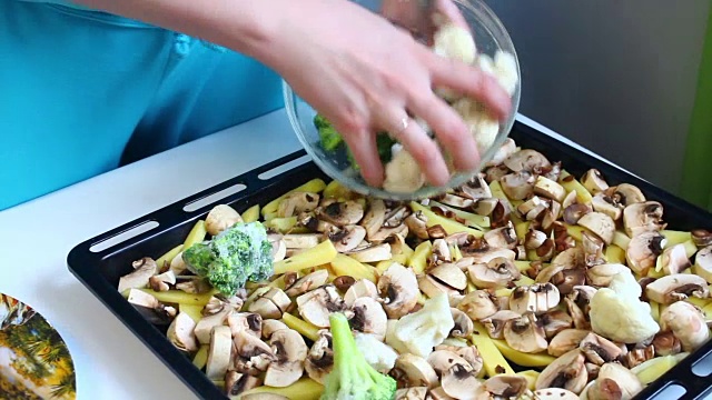 女人把花椰菜铺在烤盘上。上面已经放了碎香槟和土豆。