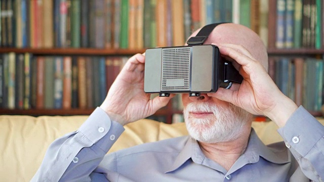 老年人在家里使用VR 360眼镜。活跃的现代老年人。书架在后台