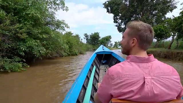 一个在亚洲旅行的年轻人，一个在缅甸茵莱湖上乘坐出租船的男人。