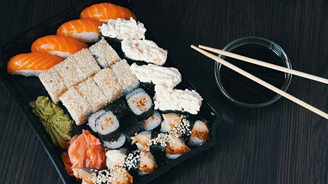 詳情圖-大型壽司套餐，包含大量的壽司，卷，壽司，手握壽司。黑色木桌上擺放著時髦的壽司，旁邊放著醬油和中式筷子