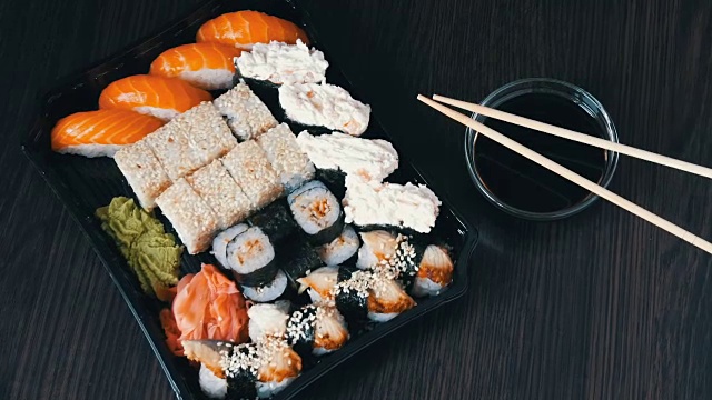 詳情圖-大型壽司套餐，包含大量的壽司，卷，壽司，手握壽司。黑色木桌上擺放著時髦的壽司，旁邊放著醬油和中式筷子