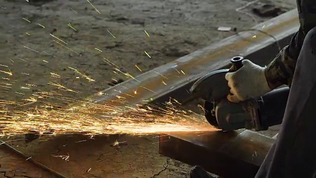 一个专业建筑工人在建筑工地打磨一大块金属的特写镜头