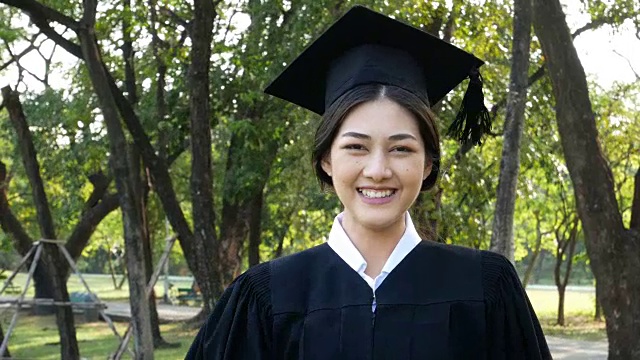 年轻的亚洲女学生戴着毕业帽和礼服，花园背景，女性与毕业概念。