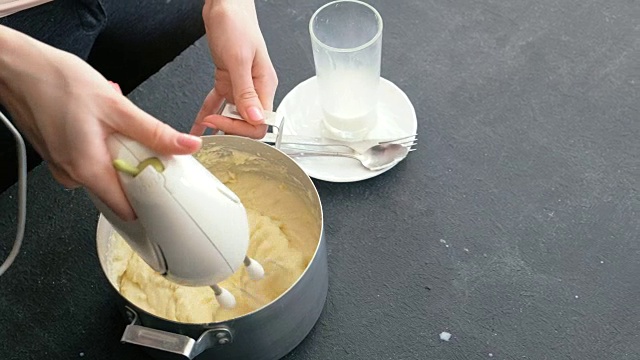 特写女子的手做土豆泥与搅拌器在平底锅。烹饪土豆泥。