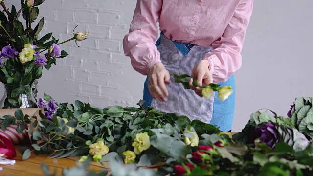 一个年轻的花商采摘了花，并检查他们为她的安排