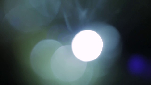 闪烁的彩灯。美丽的光漏在黑暗的背景。真正的镜头耀斑完美的抽象运动背景
