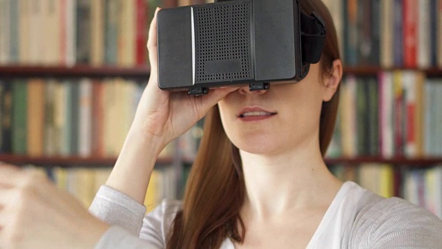 詳情圖-年輕女子在家里使用VR,360眼鏡?？吹搅钊伺d奮的東西，用手做手勢