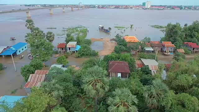 无人机视图:滑块拍摄的被洪水淹没的街道通过一个村庄，沿河有一个古老的瞭望塔