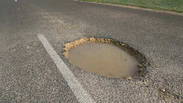 特写:道路中间的大坑里充满了浑浊的水。