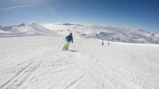 在阳光明媚的冬日，高山滑雪者在滑雪场滑雪