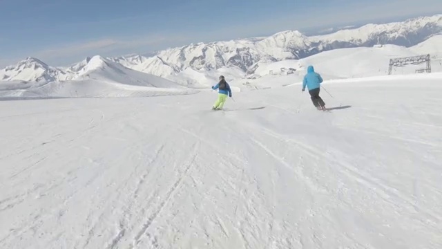 两个高山滑雪者在山坡上快速滑行