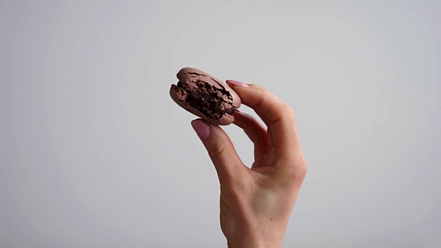 详情图-手里拿着白色背景上的彩色杏仁饼干。特写镜头。