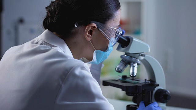 女性生物学家在显微镜下检查草药样本，实验室工作，生态学
