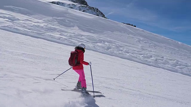 在运动中，女子滑雪者滑雪下山的山坡上