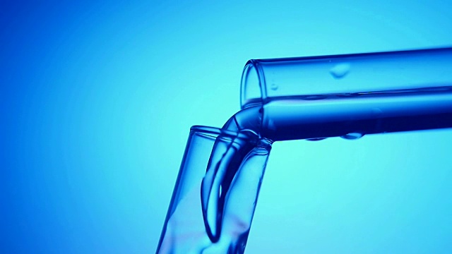 在医学实验室里，闪闪发光的液体从一个试管流入另一个试管