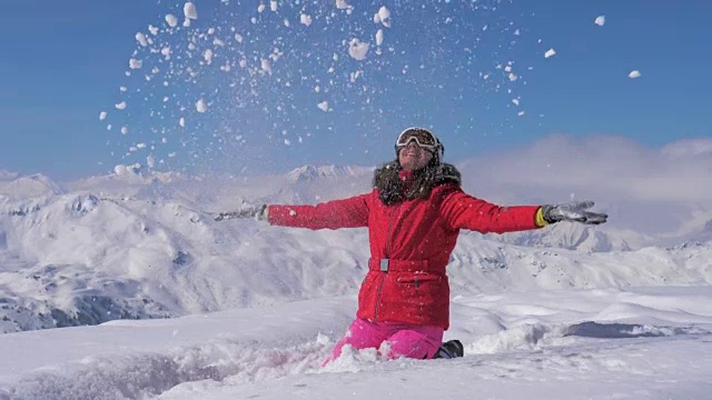 快乐的女人在一个阳光明媚的日子里玩山上的雪，慢镜头，高清。