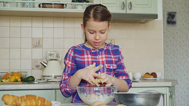 可爱的小女孩在厨房里微笑着做面团和清洁双手。她想用烤饼干给她妈妈一个惊喜