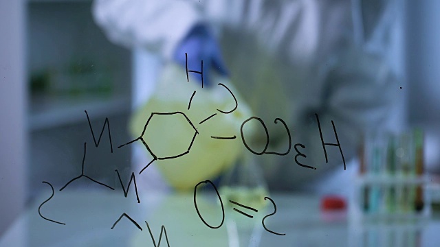 科学家将生物燃料倒入实验室烧瓶中，化学配方在玻璃板上