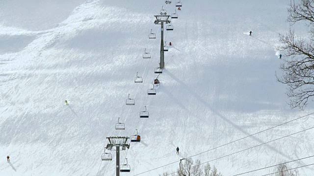 人们在冬季滑雪场的雪坡上滑雪和滑板。雪山上的滑雪电梯。冬季滑雪胜地的活动