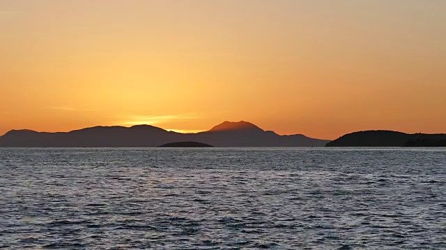 希腊伊古门尼察海岸，山间美丽的金色落日。