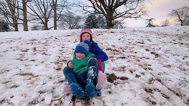 兄妹俩一起坐着雪橇从雪山上滑下来