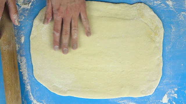 慢动作镜头。面包师用擀面杖手工准备面团。俯视图