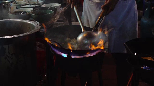 曼谷唐人街的街边炒锅起火。泰国Yaowarat市中心的美食街，厨师晚上在路边用热油炒蔬菜。