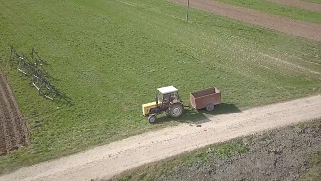 拖拉机和汽车一起在田间道路上行驶。