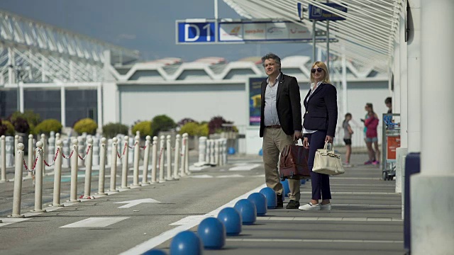 中年男女离开机场，叫出租车，正在旅行