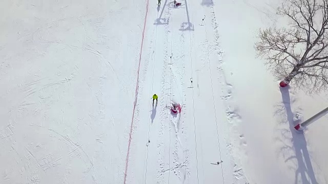 人们在冬季滑雪场的雪坡上乘坐滑雪缆车。滑雪电梯在雪山运输滑雪者和滑雪板无人机视图