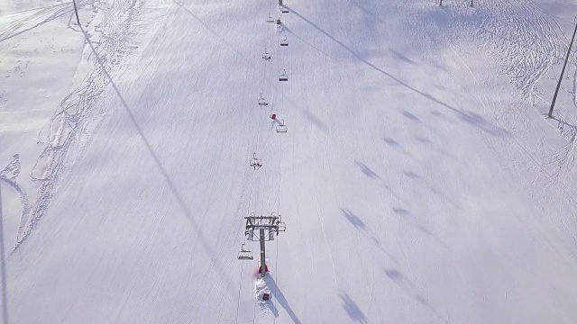 人们在冬季滑雪场的雪坡上滑雪和滑板。滑雪电梯在雪山无人机视图。滑雪胜地冬季活动鸟瞰图