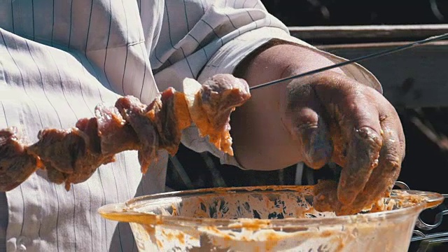 胖子把腌过的生肉串在烤肉串上。慢动作