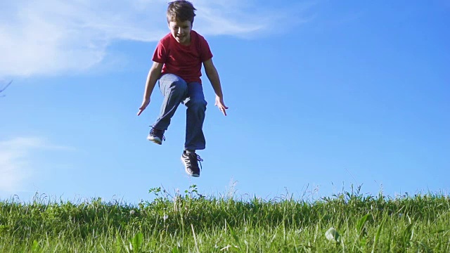 快乐的男孩在绿色的草山上跳跃