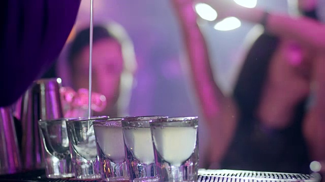 酒保将一杯含酒精的鸡尾酒倒入吧台的小玻璃杯中