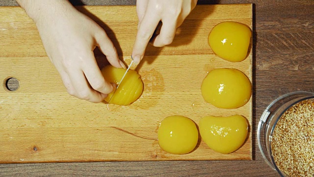 特写人类的手在家里做甜派。把桃子切成小片。