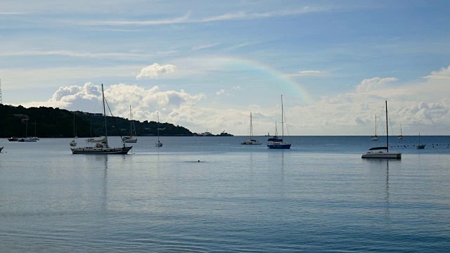 4 k的视频。在一个美丽的日子里，许多帆船停泊在海湾岸边，天空中有彩虹