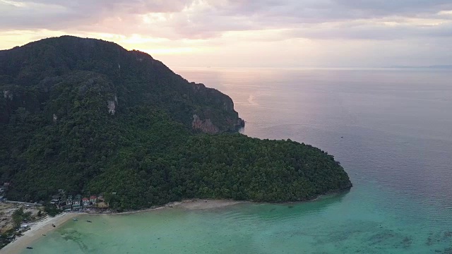 鸟瞰图:鲜艳的橙色日出隐藏在保护村庄的石灰岩山丘后面。