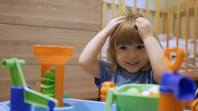 小孩玩一个五颜六色的玩具。一个学前班的小男孩在游戏室里玩一个正在发展中的玩具。