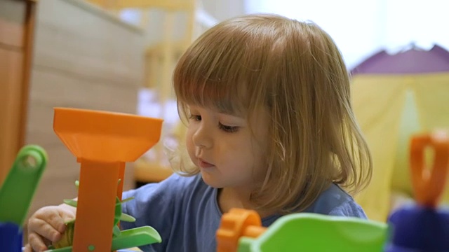 小孩玩一个五颜六色的玩具。一个学前班的小男孩在游戏室里玩一个正在发展中的玩具。