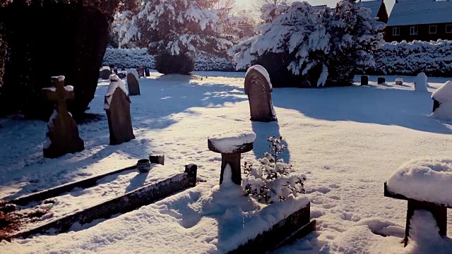 冬日的阳光照在白雪覆盖的墓碑上