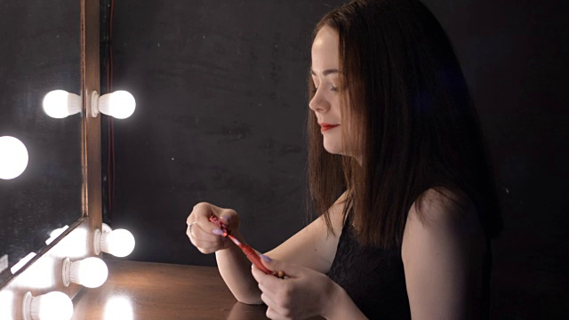 美丽的女性侧面画嘴唇坐在镜子前