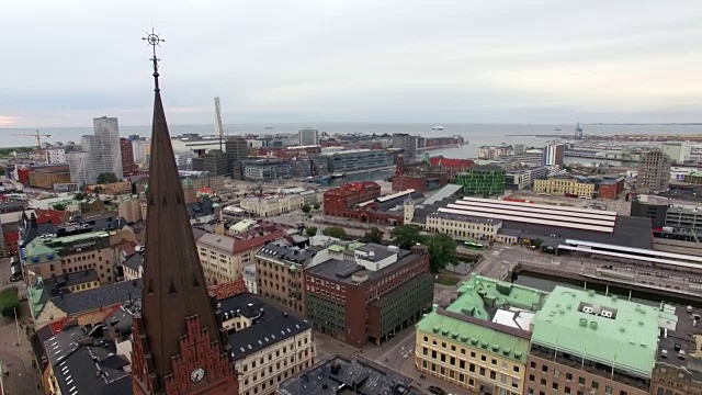 鸟瞰教堂塔尖，在Malmö市的教堂前飞下来。以城市景观建筑为背景