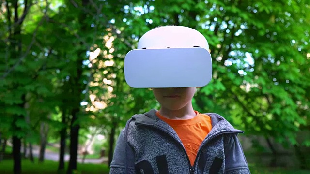 詳情圖-戴著VR眼鏡的孩子在夏天的公園里與一些東西戰(zhàn)斗，孩子們享受體驗(yàn)3D小工具技術(shù)的樂(lè)趣