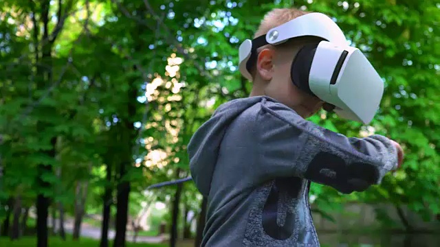 詳情圖-戴著VR眼鏡的孩子在夏天的公園里與一些東西戰(zhàn)斗，孩子們享受體驗(yàn)3D小工具技術(shù)的樂(lè)趣