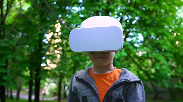 詳情圖-戴著VR眼鏡的孩子在夏天的公園里與一些東西戰(zhàn)斗，孩子們享受體驗(yàn)3D小工具技術(shù)的樂(lè)趣
