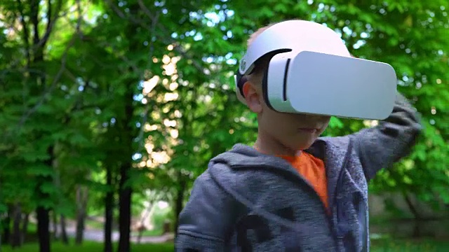詳情圖-戴著VR眼鏡的孩子在夏天的公園里與一些東西戰(zhàn)斗，孩子們享受體驗(yàn)3D小工具技術(shù)的樂(lè)趣