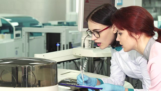 两名女生物学家在做实验时做笔记的特写