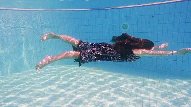 穿著禮服的年輕女孩在游泳池跳水